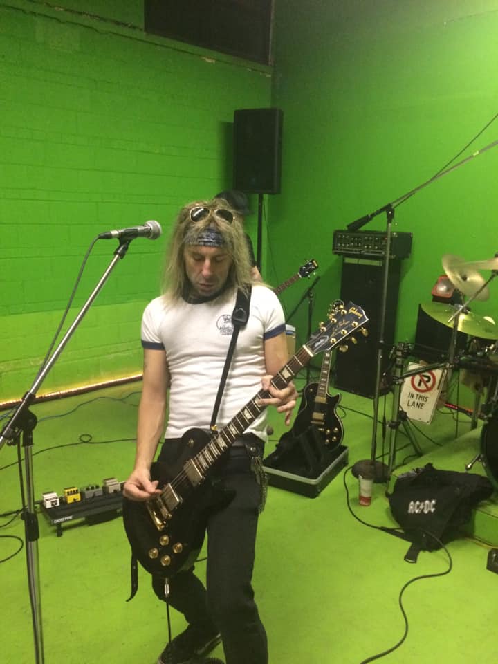 Guitarist with a headband and Les Paul at the mic in the live room