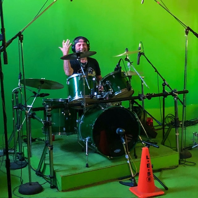 Drummer waving from behind the kit on the riser