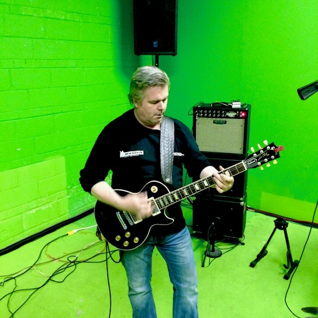 Guitarist with a black Les Paul in front of a Mesa/Boogie amp