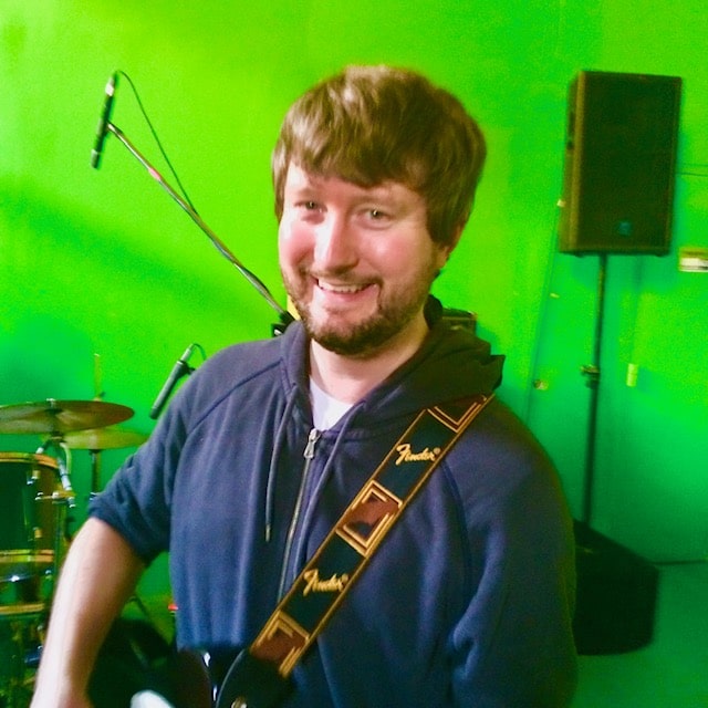 Smiling bassist in front of the green wall